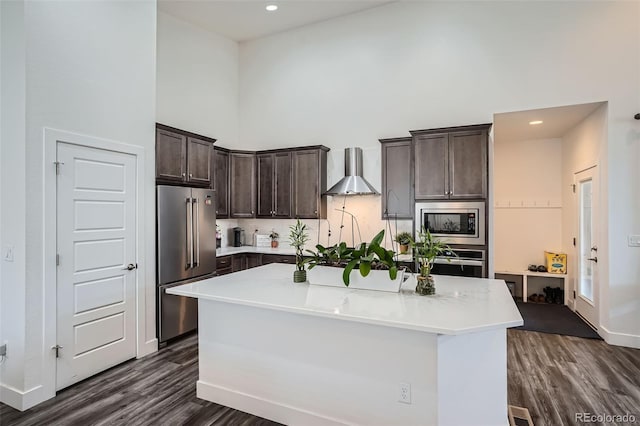 10095 E 59th Ave, Denver, CO 80238 - kitchen featuring appliances with stainless steel finishes, wall chimney range hood, a high ceiling, dark brown cabinets, and dark wood finished floors