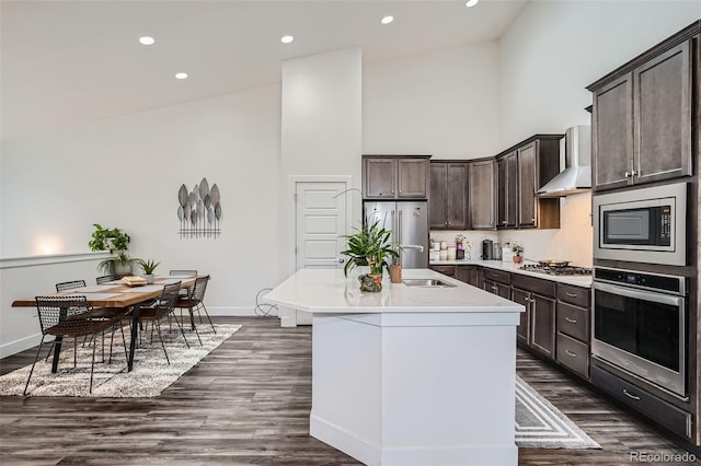 10095 E 59th Ave, Denver, CO 80238 - kitchen with stainless steel appliances, high vaulted ceiling, wall chimney range hood, dark brown cabinetry, and a center island with sink