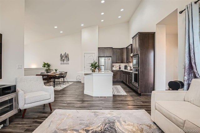 10095 E 59th Ave, Denver, CO 80238 - kitchen featuring appliances with stainless steel finishes, open floor plan, dark brown cabinetry, high vaulted ceiling, and a center island with sink