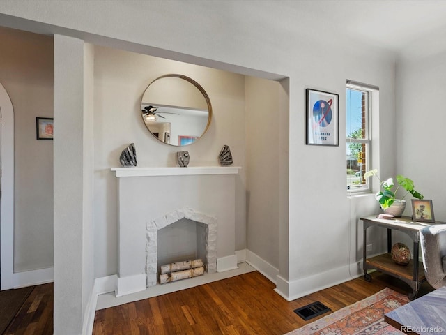 living room with arched walkways, a fireplace with flush hearth, wood finished floors, and ceiling fan