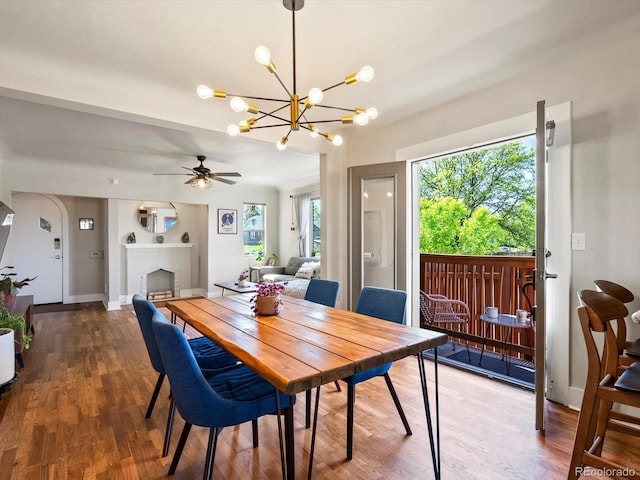 dining area featuring a chandelier, wood finished floors, a fireplace, and ceiling fan