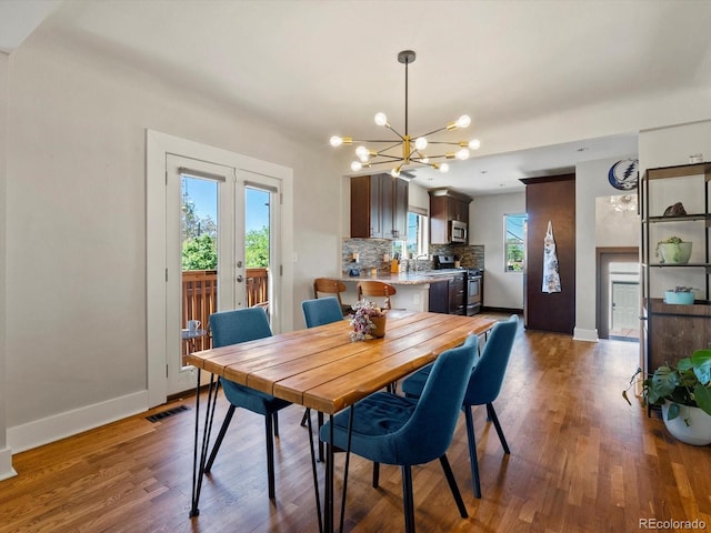 dining space featuring a chandelier, baseboards, wood finished floors, and french doors