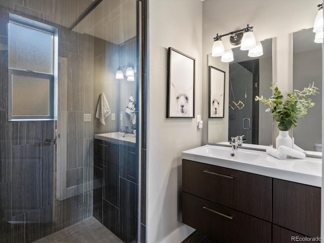 full bath featuring a shower stall, vanity, and baseboards