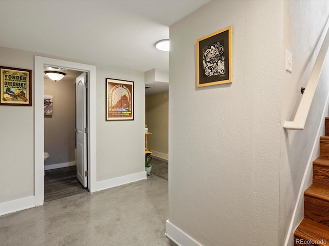 hall with stairway, baseboards, and finished concrete flooring