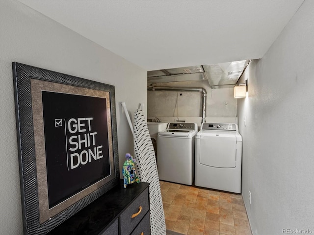 laundry area featuring washer and clothes dryer and light stone finish floors
