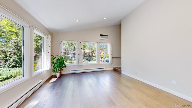 spare room featuring a baseboard heating unit, hardwood / wood-style floors, and lofted ceiling