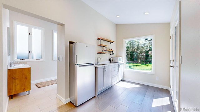 kitchen featuring white cabinets, sink, white appliances, light wood-type flooring, and lofted ceiling