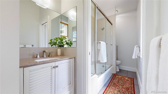 full bathroom with toilet, tile floors, vanity, and shower / bath combination with glass door