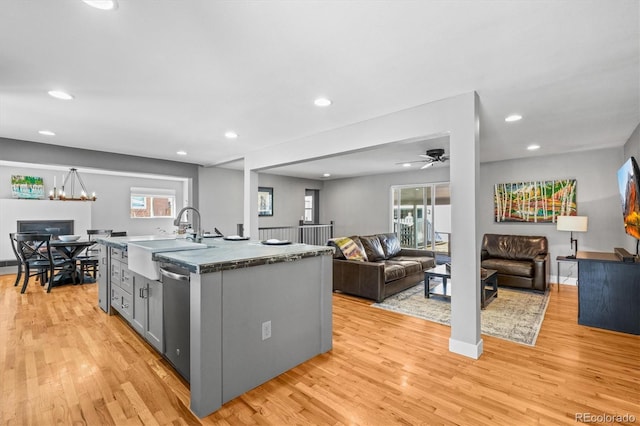 kitchen featuring gray cabinets, a sink, open floor plan, light wood-style floors, and dishwasher