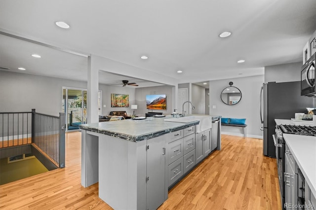 kitchen with light wood-type flooring, a sink, open floor plan, recessed lighting, and stainless steel appliances