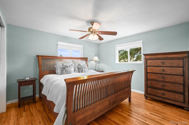 bedroom featuring baseboards, a textured ceiling, and light wood finished floors