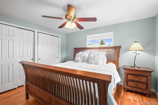 bedroom featuring baseboards, a ceiling fan, light wood-type flooring, and multiple closets