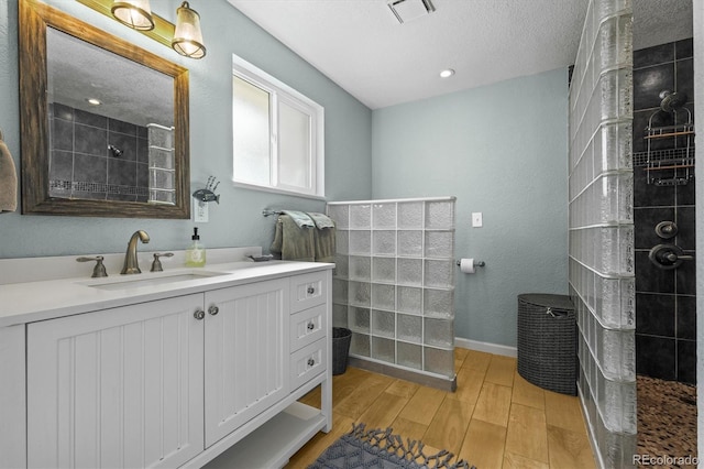 bathroom featuring visible vents, baseboards, walk in shower, wood finished floors, and vanity