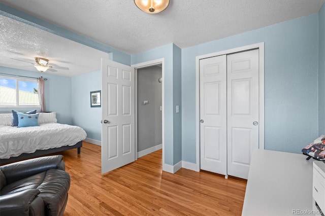 bedroom with a closet, baseboards, a textured ceiling, and light wood finished floors