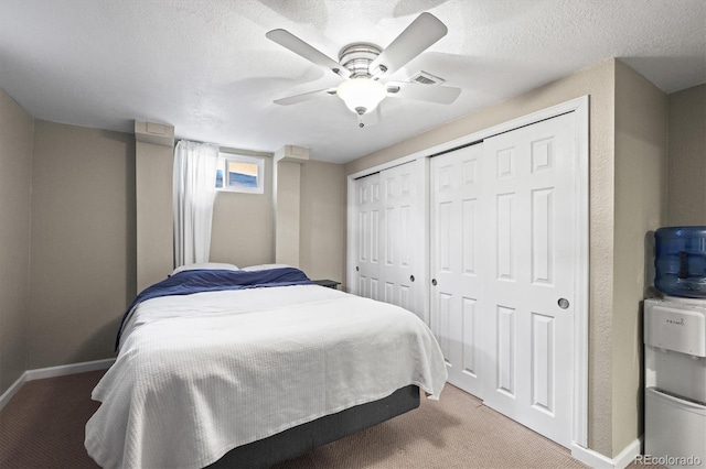 carpeted bedroom with multiple closets, a ceiling fan, baseboards, and a textured ceiling