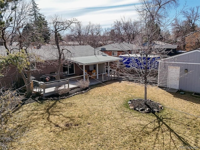 back of house featuring an outbuilding, a storage shed, and a yard