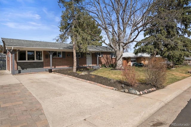 ranch-style house featuring brick siding, covered porch, driveway, and a front lawn