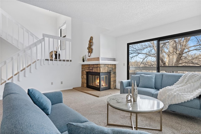 living room with carpet flooring, a fireplace, and a textured ceiling