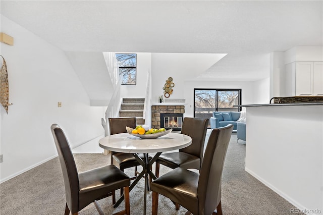 dining space with light carpet and a fireplace