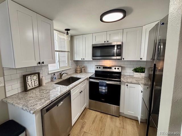 6895 W 84th Way Unit 4, Arvada, CO 80003 - kitchen with appliances with stainless steel finishes, a sink, light wood finished floors, and white cabinetry