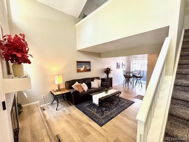 6895 W 84th Way Unit 4, Arvada, CO 80003 - living room featuring stairway, wood finished floors, high vaulted ceiling, and baseboards
