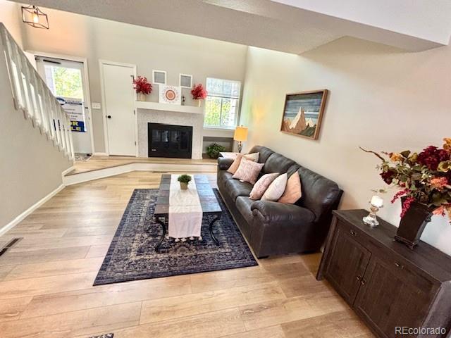 6895 W 84th Way Unit 4, Arvada, CO 80003 - living room with light wood-style flooring, stairway, a glass covered fireplace, and baseboards