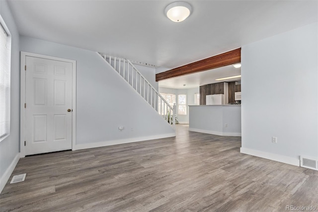 unfurnished living room with beam ceiling and wood-type flooring