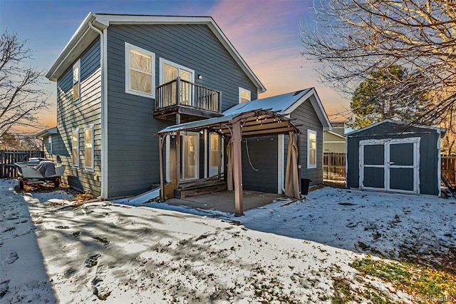 snow covered property featuring a balcony and a shed