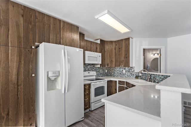 kitchen featuring sink, dark wood-type flooring, tasteful backsplash, kitchen peninsula, and white appliances