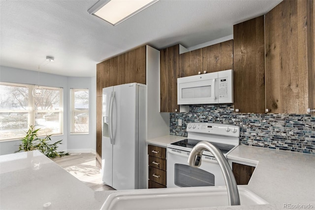 kitchen with decorative backsplash, a textured ceiling, white appliances, and hanging light fixtures