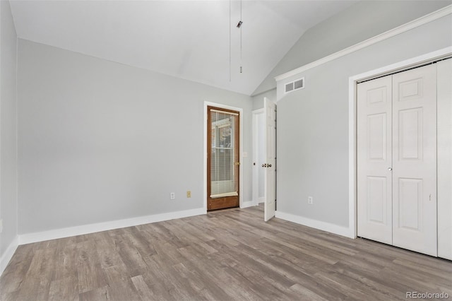 unfurnished bedroom with light hardwood / wood-style floors and lofted ceiling