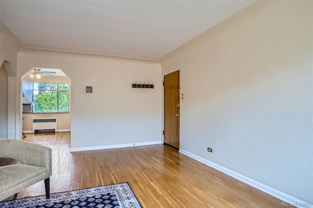 1523 Ivy St Unit 6, Denver, CO 80220 - unfurnished living room featuring radiator heating unit, light wood finished floors, a ceiling fan, arched walkways, and cooling unit