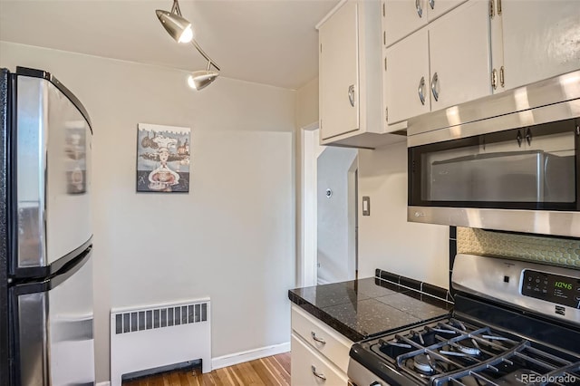 1523 Ivy St Unit 6, Denver, CO 80220 - kitchen with appliances with stainless steel finishes, radiator, light wood finished floors, and white cabinetry