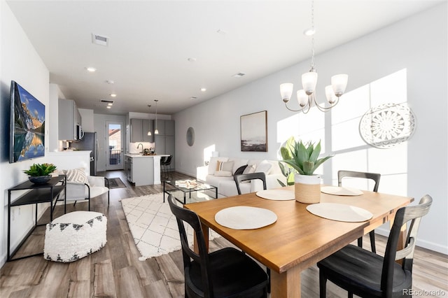 dining area with hardwood / wood-style flooring and an inviting chandelier