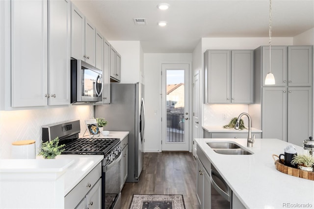 kitchen featuring pendant lighting, sink, gray cabinets, appliances with stainless steel finishes, and dark hardwood / wood-style floors