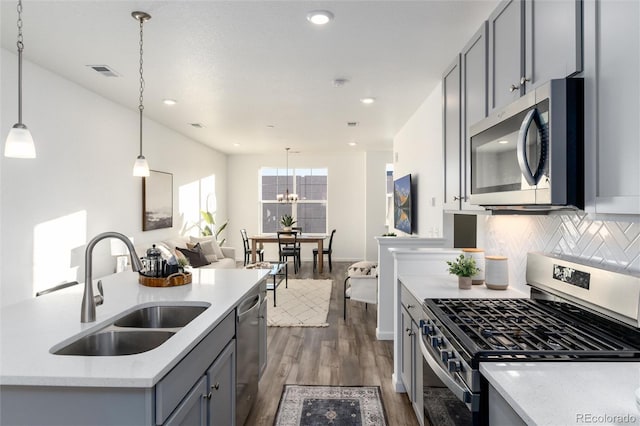 kitchen with sink, hanging light fixtures, gray cabinets, stainless steel appliances, and backsplash