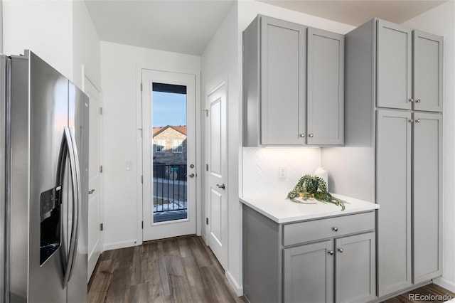 kitchen featuring tasteful backsplash, dark hardwood / wood-style floors, gray cabinetry, and stainless steel fridge with ice dispenser