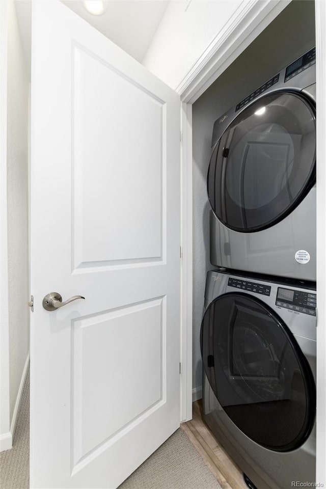 washroom with stacked washer and clothes dryer and light hardwood / wood-style flooring