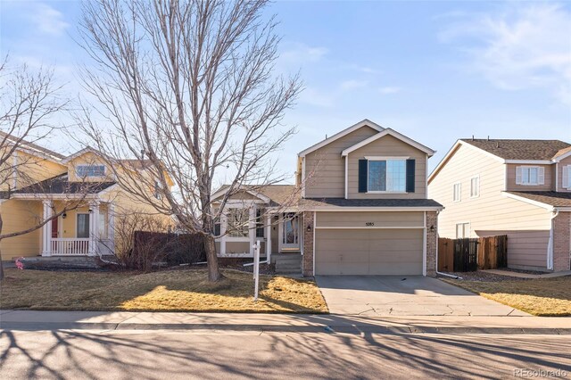 traditional home featuring a garage, concrete driveway, roof with shingles, fence, and brick siding