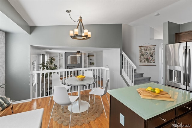 dining room with stairs, ceiling fan with notable chandelier, and light wood-type flooring