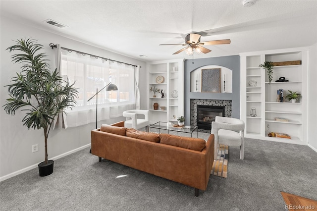 carpeted living area with a textured ceiling, ceiling fan, a fireplace, visible vents, and baseboards