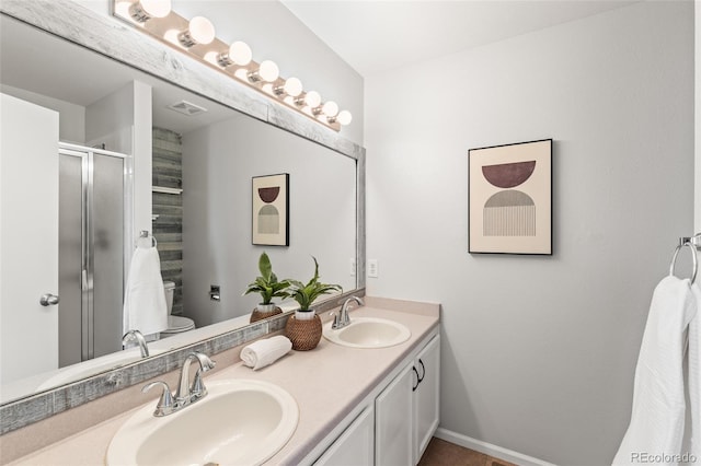 full bath with a sink, a shower stall, toilet, and double vanity