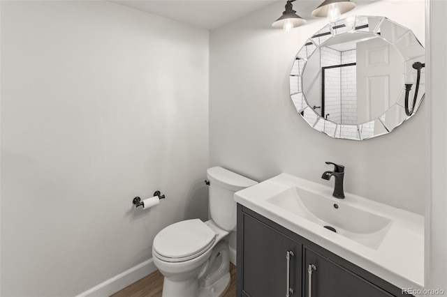 bathroom featuring wood finished floors, vanity, toilet, and baseboards