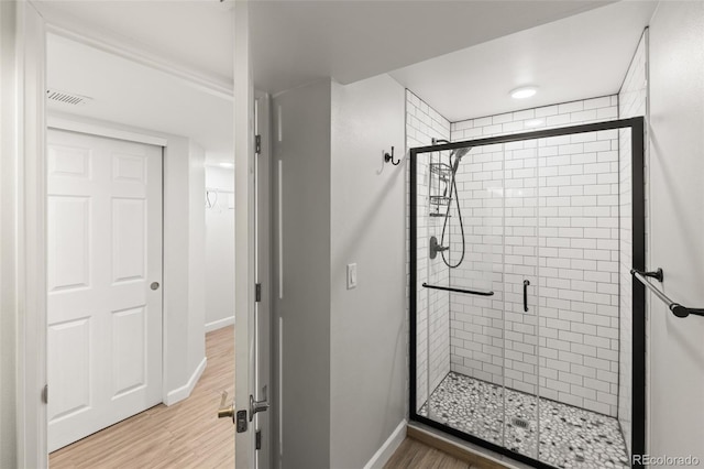 full bathroom with baseboards, a shower stall, visible vents, and wood finished floors