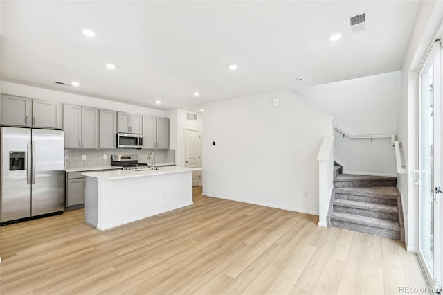 kitchen with appliances with stainless steel finishes, gray cabinets, light countertops, light wood-type flooring, and recessed lighting