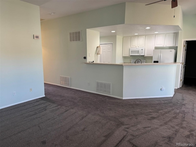 interior space featuring white appliances, visible vents, and white cabinets