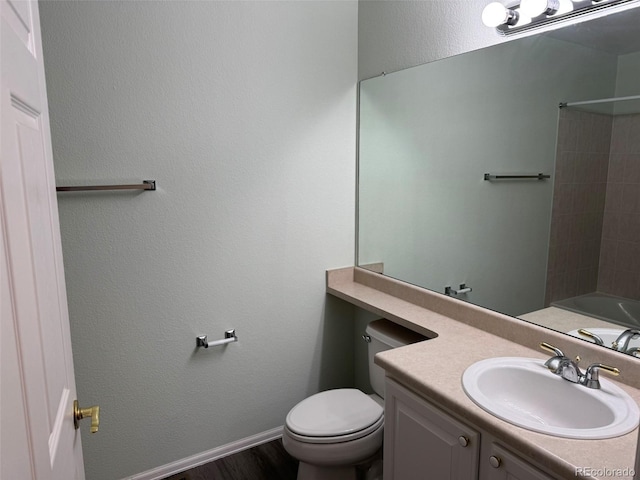 bathroom with a textured wall, toilet, vanity, wood finished floors, and baseboards