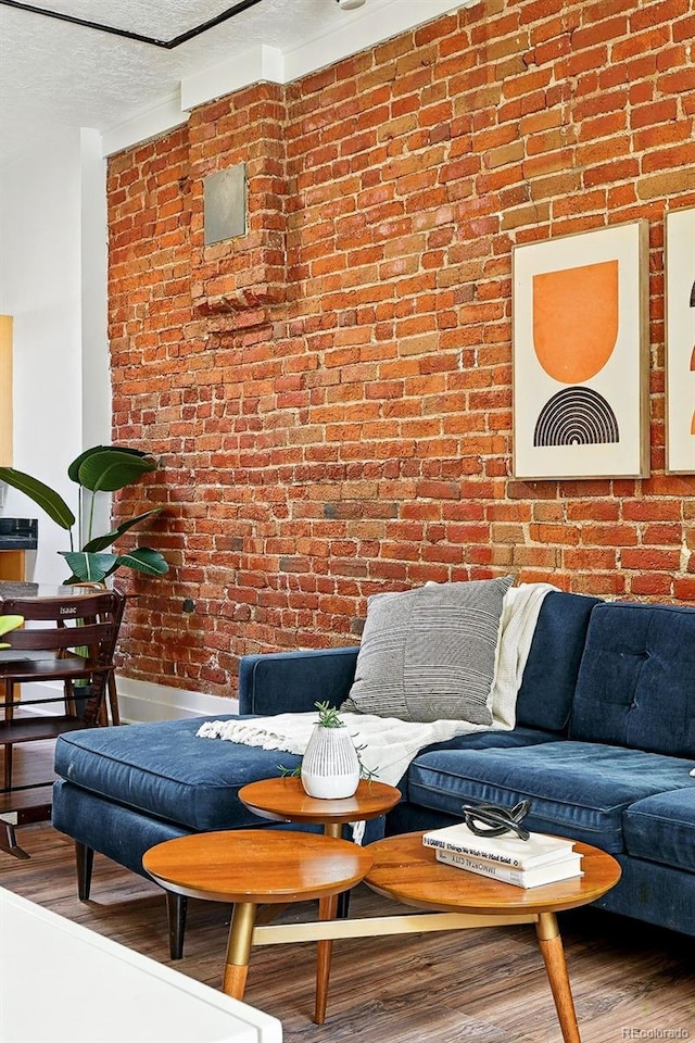 361 Elati St, Denver, CO 80223 - living room featuring brick wall, wood finished floors, and a textured ceiling