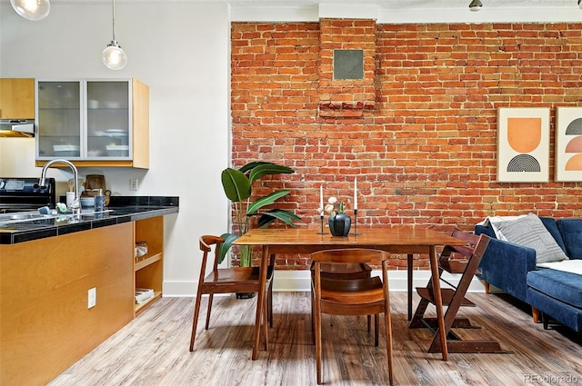 361 Elati St, Denver, CO 80223 - dining area featuring brick wall and light wood-type flooring