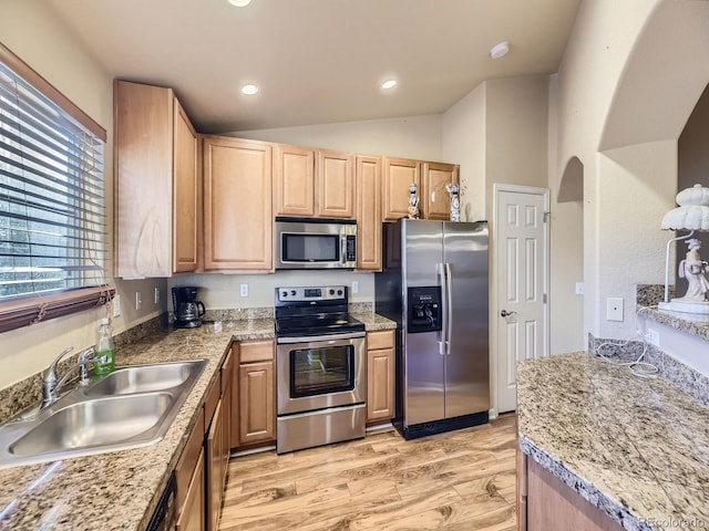 kitchen featuring light brown cabinetry, sink, vaulted ceiling, light wood-type flooring, and appliances with stainless steel finishes